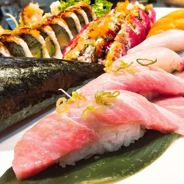 A vibrant platter of assorted sushi, including nigiri, maki rolls, and a hand roll.