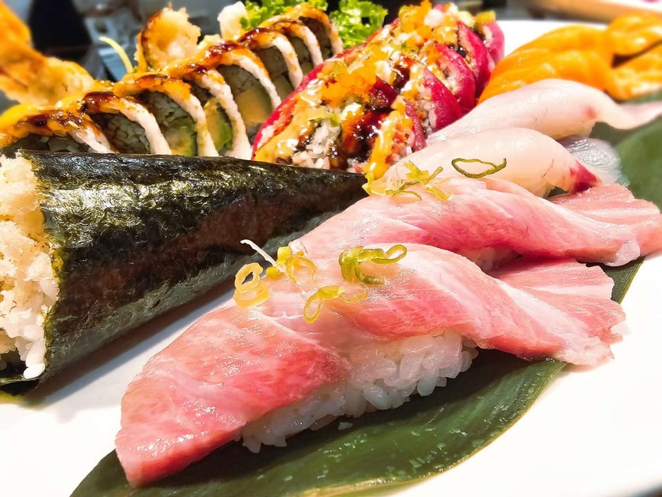 A vibrant platter of assorted sushi, including nigiri, maki rolls, and a hand roll.