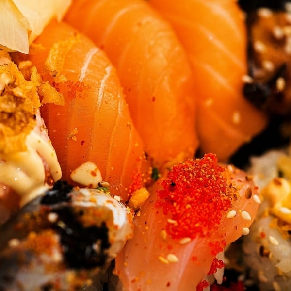 Close-up of a vibrant sushi platter featuring salmon nigiri, rolls with roe, and crispy toppings.