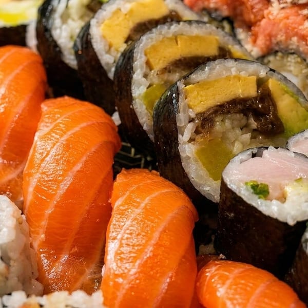 A close-up of a vibrant sushi platter featuring salmon nigiri, various maki rolls, and sashimi.